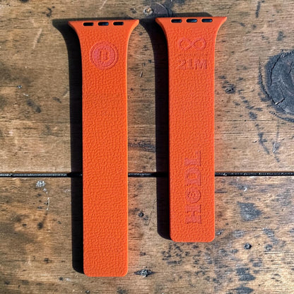Orangefarbenes Silikonarmband kompatibel mit Apple Watch ohne Uhr, liegend auf rustikalem Holztisch