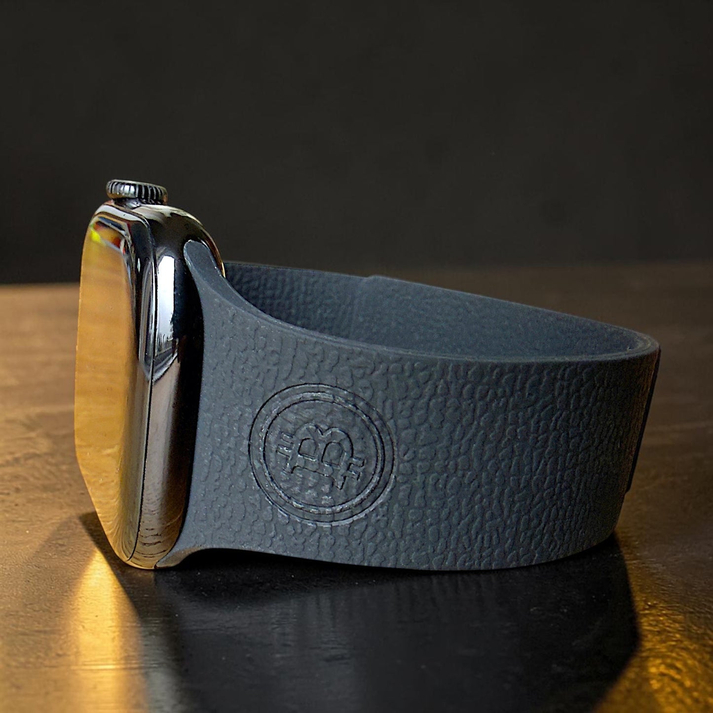 Nahaufnahme eines schwarzen Apple Watch Armbands mit geprägtem Bitcoin BTC Logo im Silikon