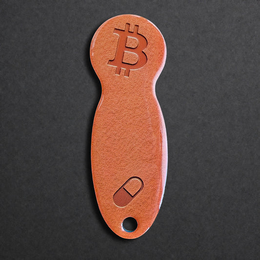 Bitcoin Einkaufswagenlöser aus Edelstahl in Orange Pill, frontal von oben fotografiert, kompakt und schlüsselbundtauglich
