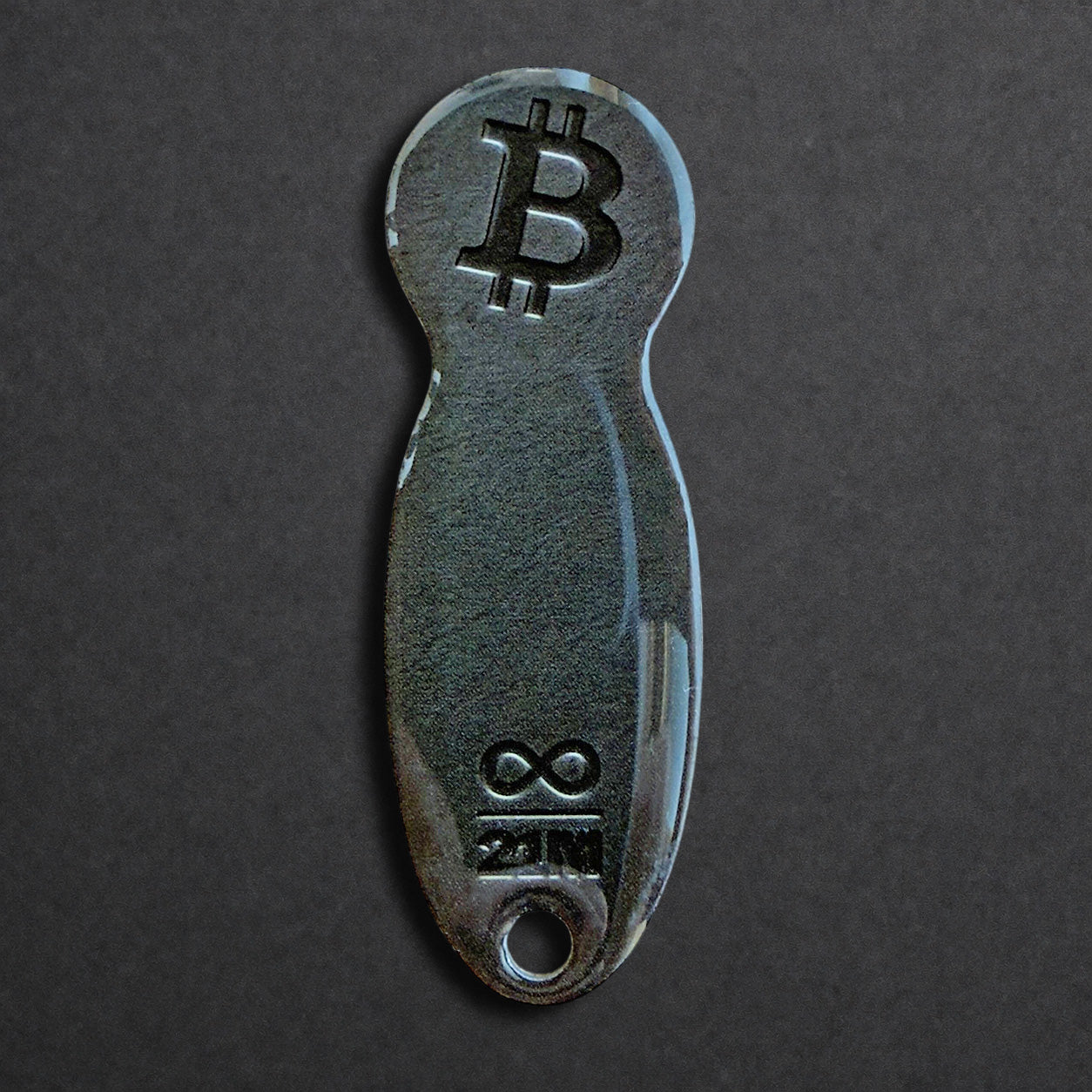 Bitcoin Einkaufswagenlöser aus Edelstahl in Schwarz Matt frontal von oben fotografiert, kompakt und schlüsselbundtauglich
