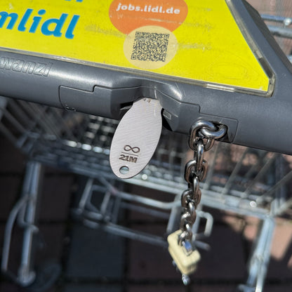 Bitcoin Einkaufswagenlöser in Edelstahl Optik im Münzschlitz eines Einkaufswagens eingesteckt als praktische Alternative zur Münze