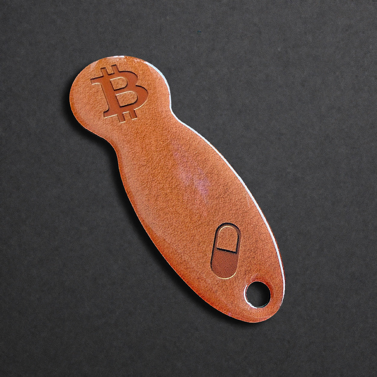 Detailaufnahme eines Bitcoin Einkaufswagenlösers aus Edelstahl in Orange Pill in schräger Perspektive