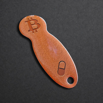 Detailaufnahme eines Bitcoin Einkaufswagenlösers aus Edelstahl in Orange Pill in schräger Perspektive