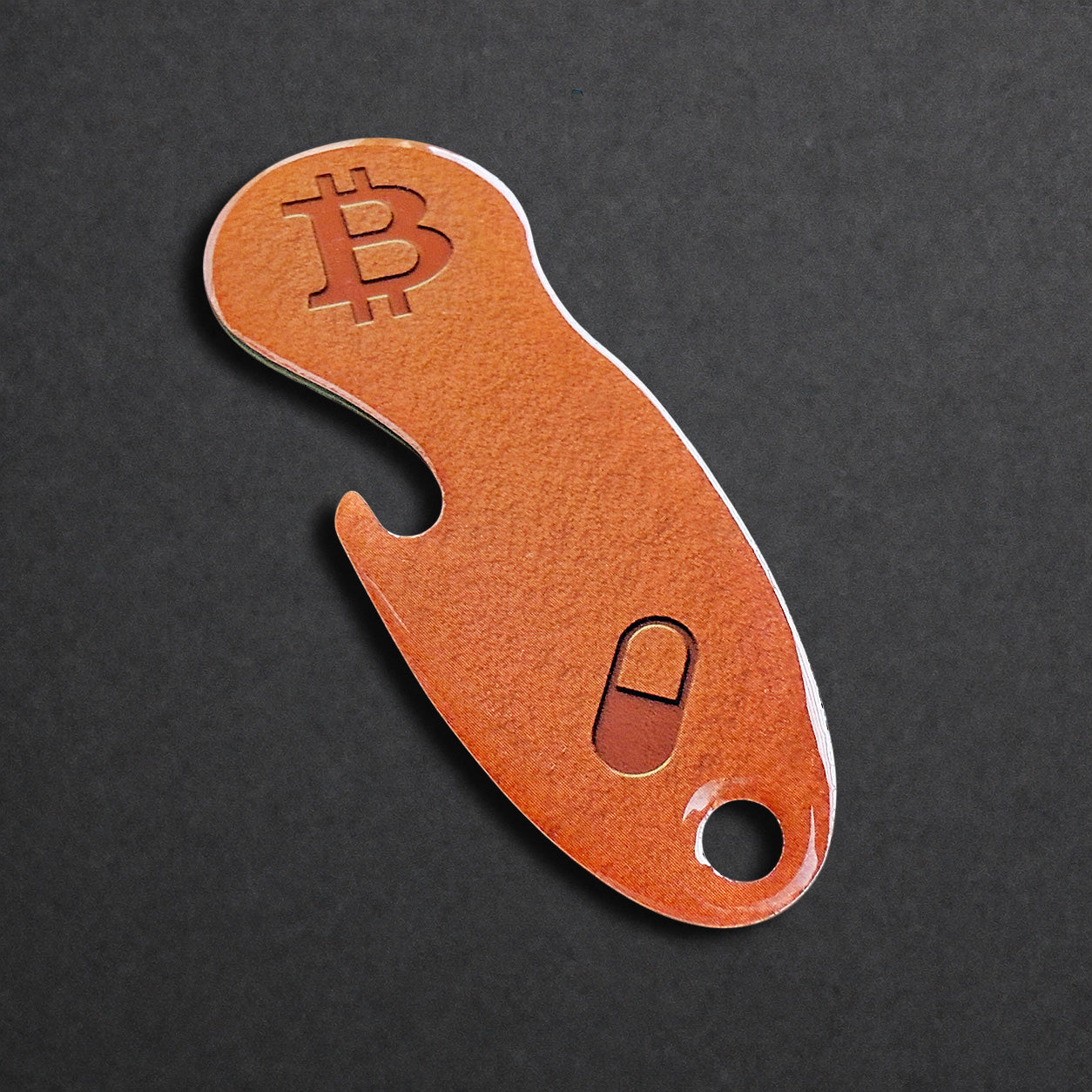 Detailaufnahme eines Bitcoin Einkaufswagenlösers aus Edelstahl in Orange Pill mit Flaschenöffner in schräger Perspektive