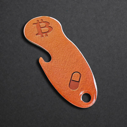Detailaufnahme eines Bitcoin Einkaufswagenlösers aus Edelstahl in Orange Pill mit Flaschenöffner in schräger Perspektive
